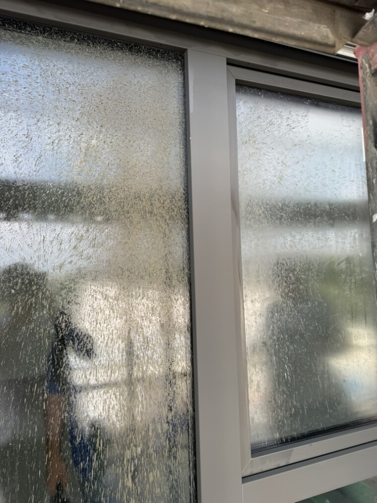 Detailaufnahme der starken flächigen Beläge und Laufspuren auf dem Fensterglas vor der Reinigung