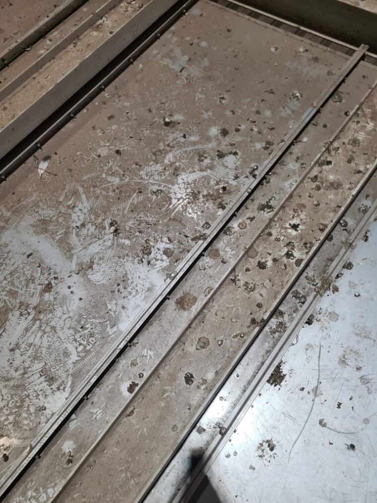 Metallflächen und Rahmen mit Taubenkot und Staubablagerungen vor der Reinigung.