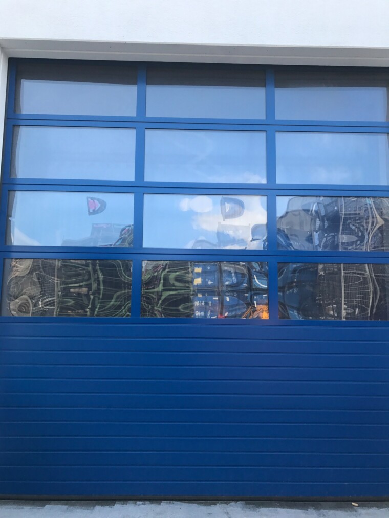 Dasselbe blaue Sektionaltor nach der Reinigung mit klareren Glasfeldern und sichtbaren Spiegelungen.