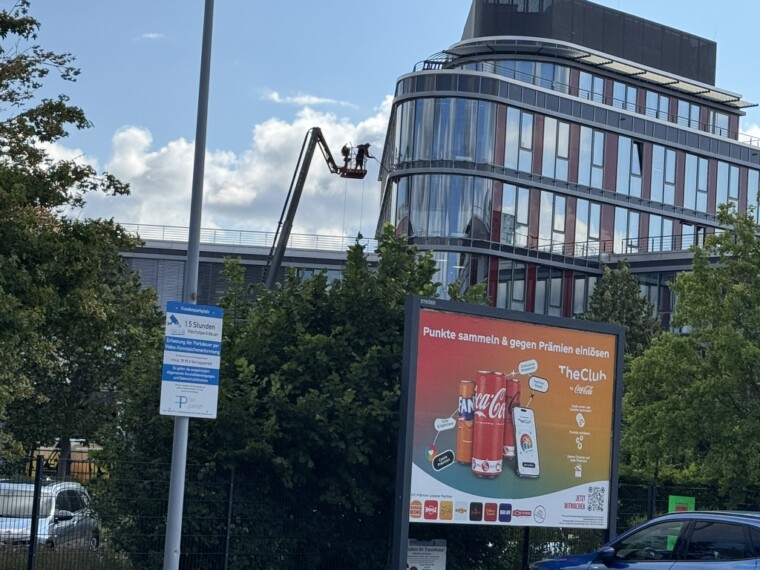 Fassadenreinigung mit Hubarbeitsbühne an einem mehrgeschossigen Gebäude mit Glasfassade.