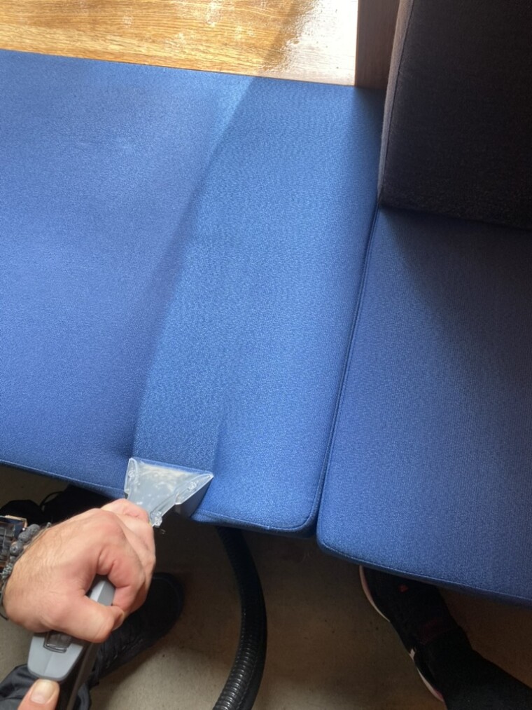 Transparente Reinigungsdüse auf einem blauen Sitzpolster während der Polsterreinigung